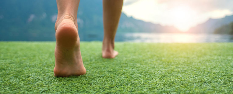person's feet walking on the grass