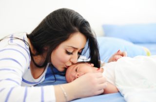 A mother kisses her newborn child.