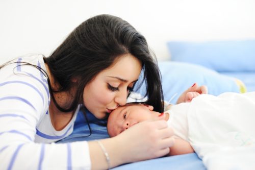 A mother kisses her newborn child.