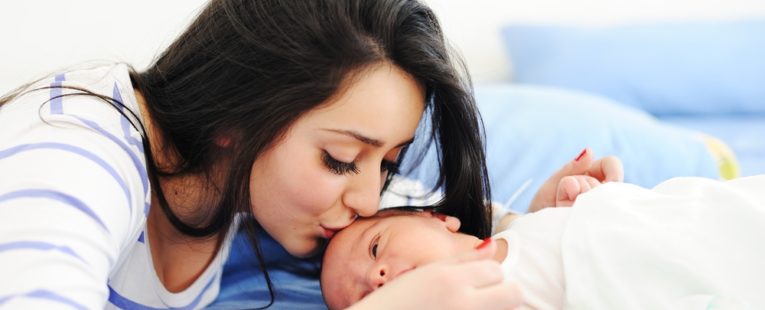 A mother kisses her newborn child.