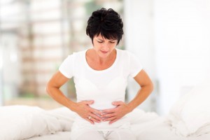 Middle-aged woman experiencing a common heart attack symptom - severe stomach pain