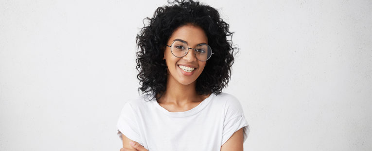 Young African-American woman in glasses smiling.