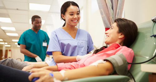 Nurse smiling at blood donor as donor gives blood