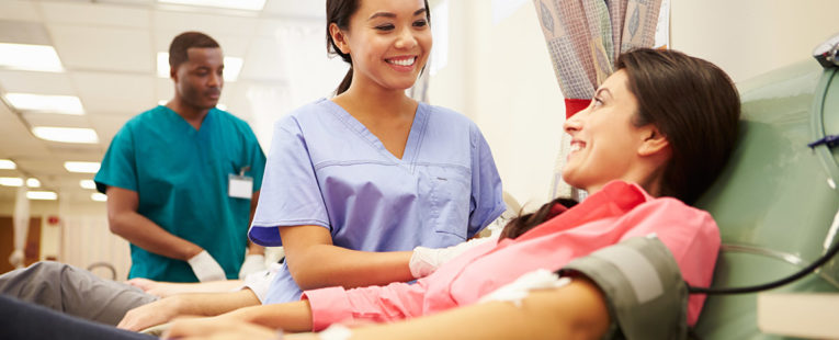 Nurse smiling at blood donor as donor gives blood