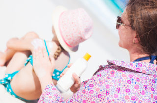 mom applying sunscreen to daughter at beach