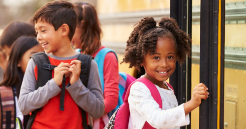 young girl with a backpack boarding a school bus