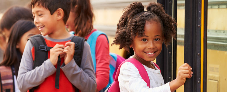 young girl with a backpack boarding a school bus