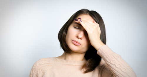 Woman with hand on forehead suffering from a headache