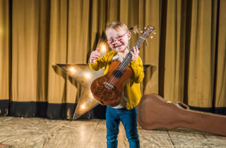 Ryli VanHoevln on stage with a guitar.