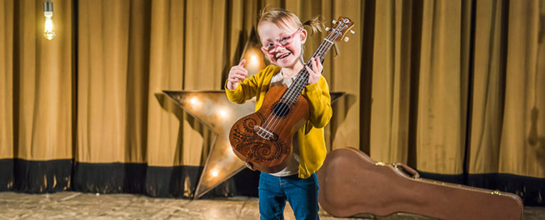 Ryli VanHoevln on stage with a guitar.