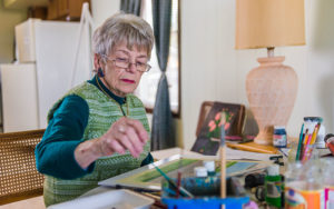 Dolores Ott paints in her living room.