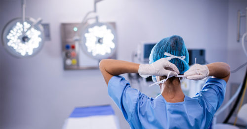 Surgical nurse putting on mask in an operating room