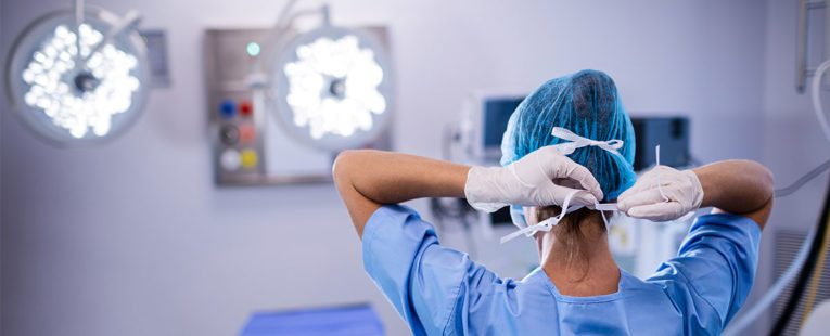 Surgical nurse putting on mask in an operating room