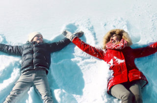 Mother and daughter making snow angels in winter.