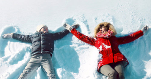 Mother and daughter making snow angels in winter.