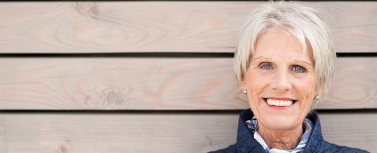 Older woman standing outside wearing a winter coat smiling.