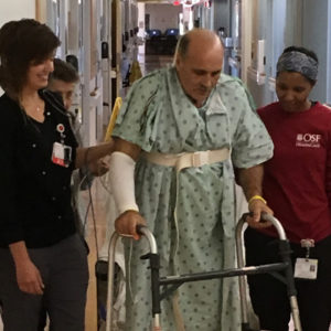 Dennis VanMeter walking in the hospital with nursing staff.