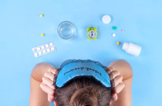 woman who cannot sleep looking at melatonin and other sleep aids on a tabletop.