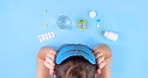 woman who cannot sleep looking at melatonin and other sleep aids on a tabletop.