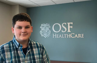 Kaleb stands by OSF HealthCare Children's Hospital sign