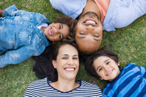 family laying on ground in park.