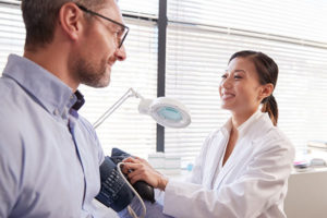 man getting blood pressure checked by female health care provider