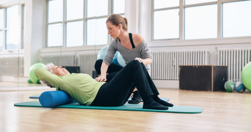 senior woman doing pelvic floor exercises in gym with trainer