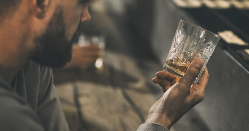 heart conscious alchohol drinker stares at glass of whiskey