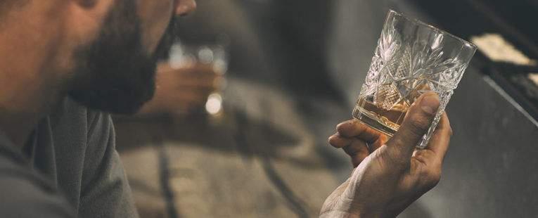 heart conscious alchohol drinker stares at glass of whiskey