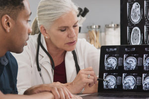 Female physician reviewing CT scan imaging for male patient with aneurysm