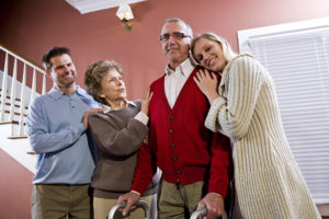 Senior male hospice patient with walker surrounded by family