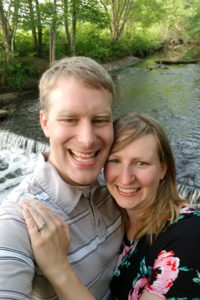 Young engaged couple standing near scenic waterfall