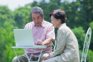senior couple outdoors researching Medicare plans on laptop