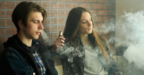Teenage boy and girl vaping