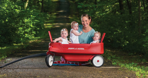 Colwell triplets and their mother in a wagon outdoors.