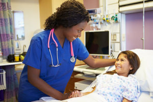 Pediatric nurse holding young girl patient's hand
