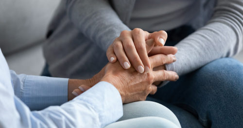 Grief support group participants holding hands