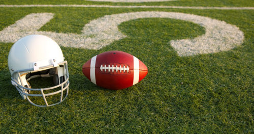 Football and helmet on field