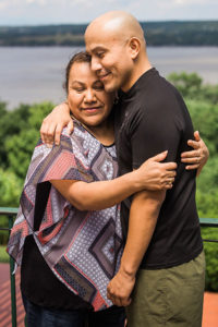 Osvaldo Ramirez and wife embrace on river bluff.