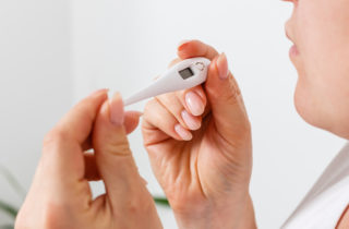 Woman taking temperature with thermometer