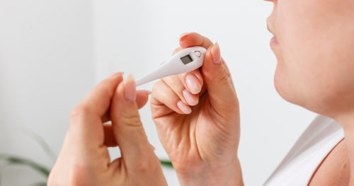 Woman taking temperature with thermometer