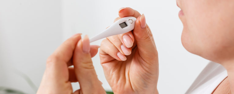 Woman taking temperature with thermometer