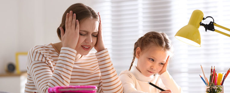 Stressed mother helping daughter with homework.