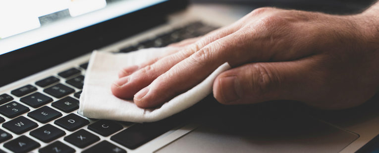 Man cleaning laptop in office.