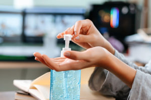 Woman in office using hand sanitizer.