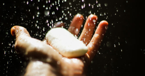 Man's hands holding a bar of soap getting wet.