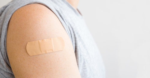 Young adult male with bandage on arm after receiving vaccine.