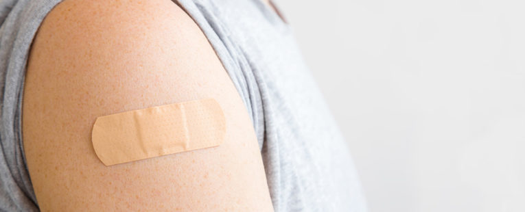 Young adult male with bandage on arm after receiving vaccine.