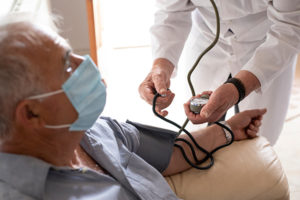 Senior male with hypertension getting blood pressure checked in physician's office.