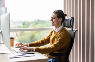Young adult male professional in office performing computer programming.